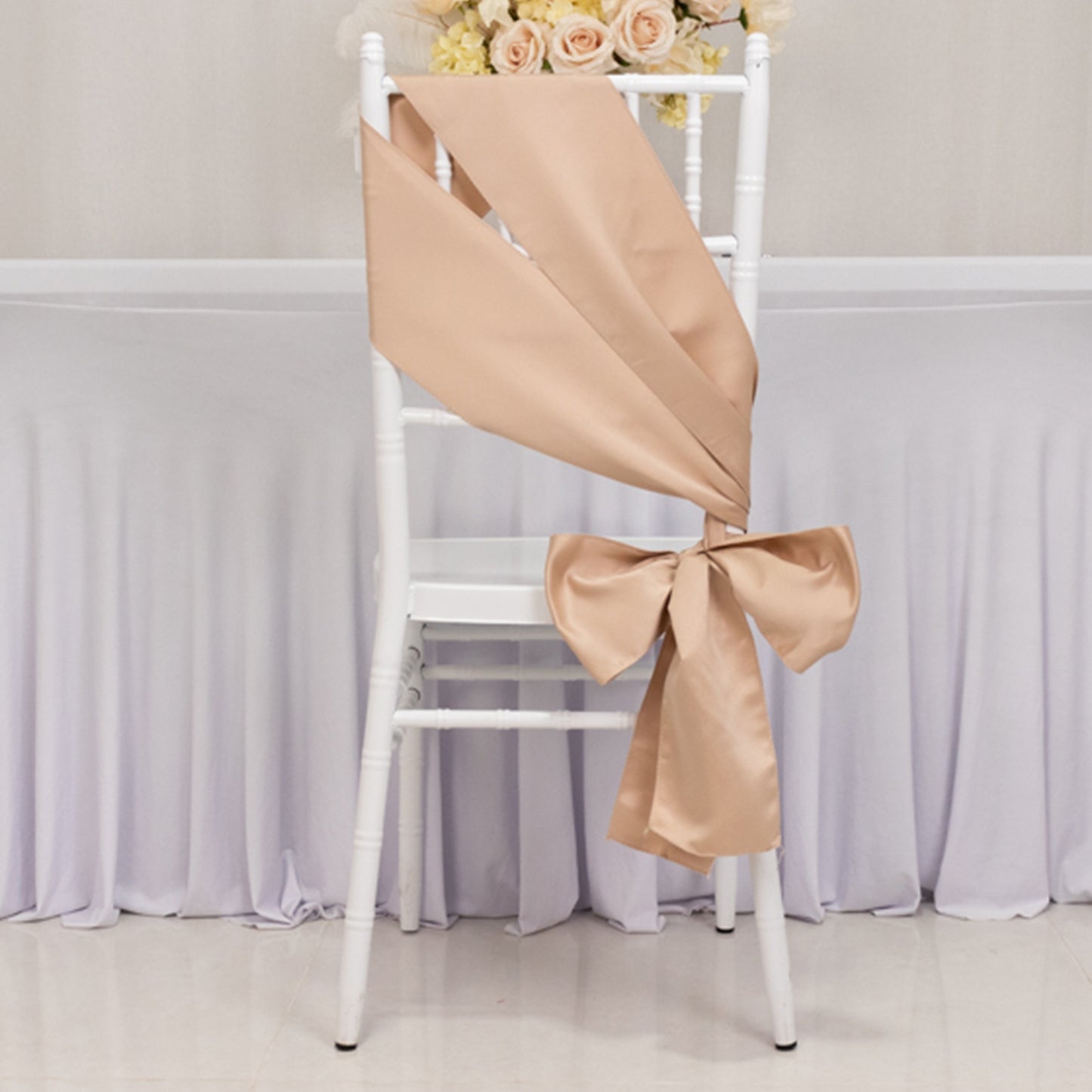 Nude satin chair sash and bow on a white chair.