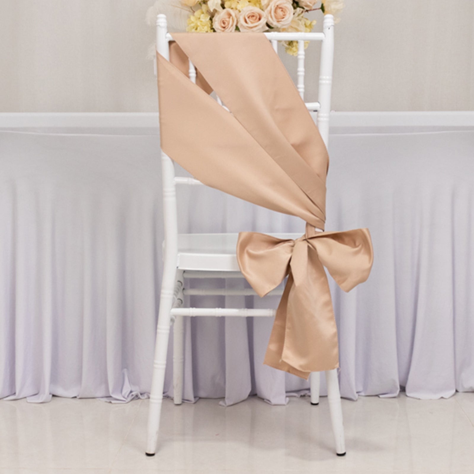 Nude satin chair sash and bow on a white chair.