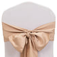 Nude satin chair sashes with bows for elegant event decor.