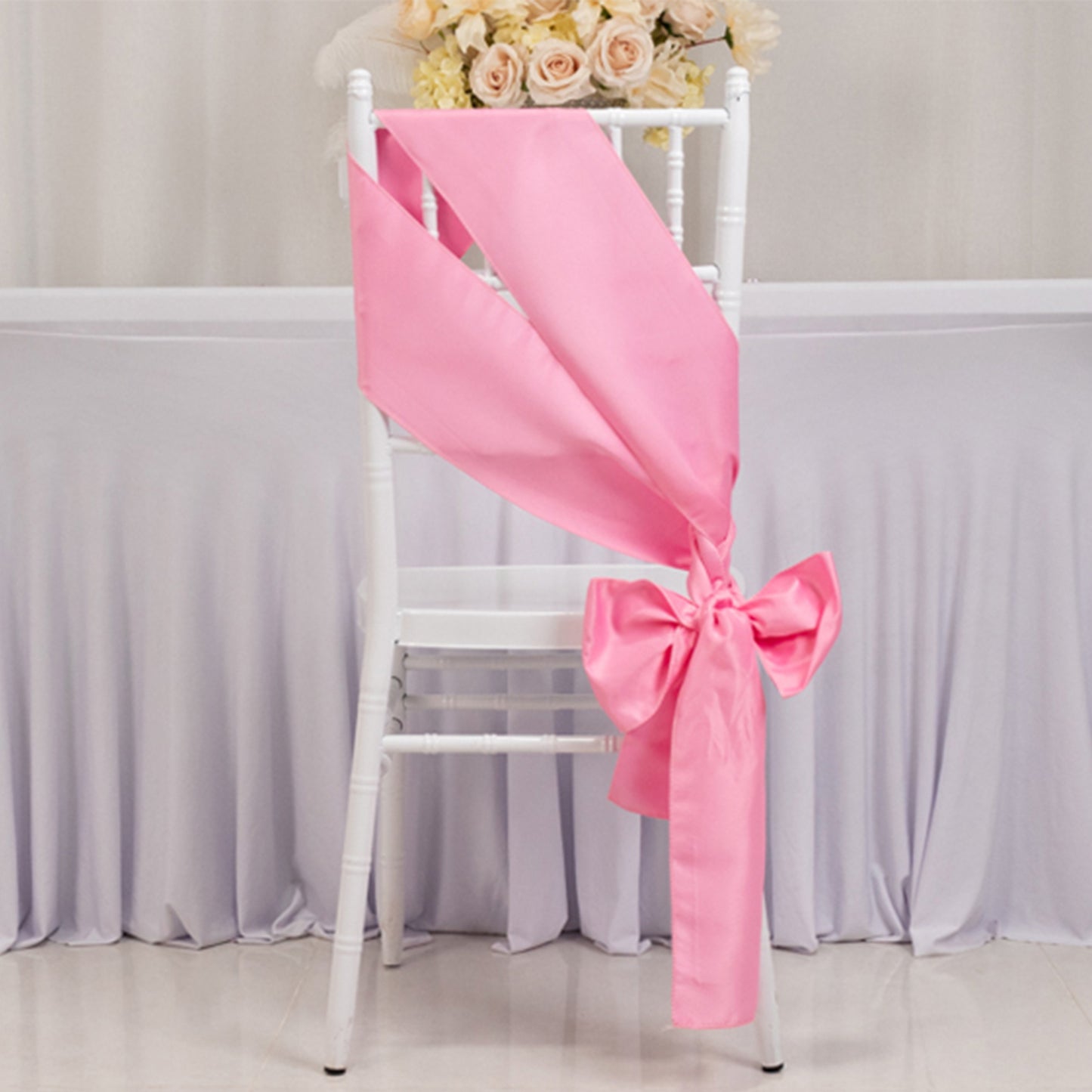 Pink satin chair sash with bow, perfect for elegant events.