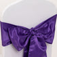 Purple satin chair sash bow on a white chair.
