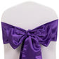 Purple satin chair sash bow on a white chair.