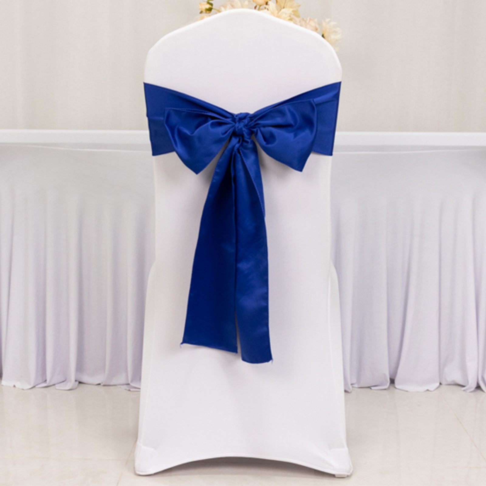 Royal blue satin chair sash bow on a white chair.