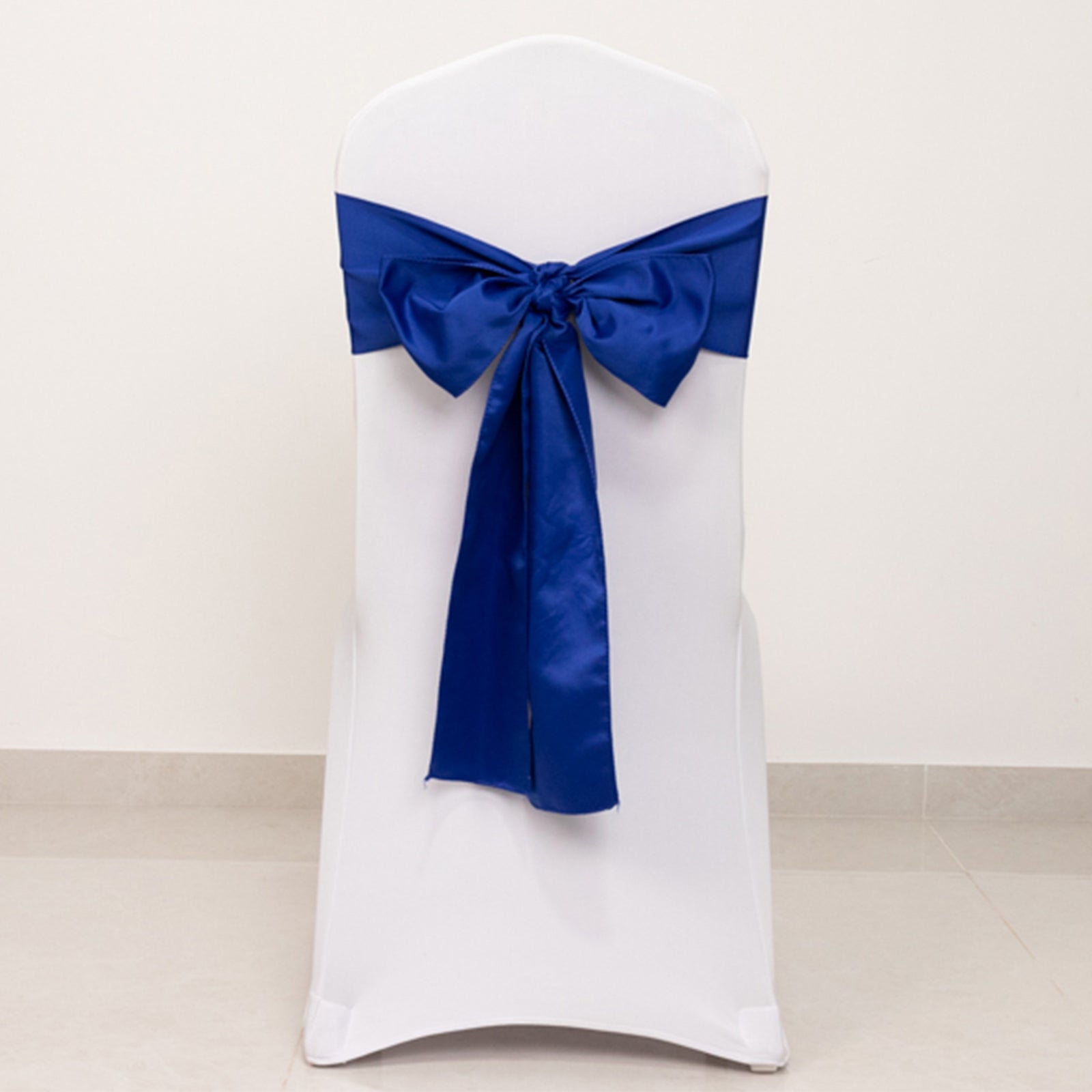 Royal blue satin chair sash bow on a white chair.