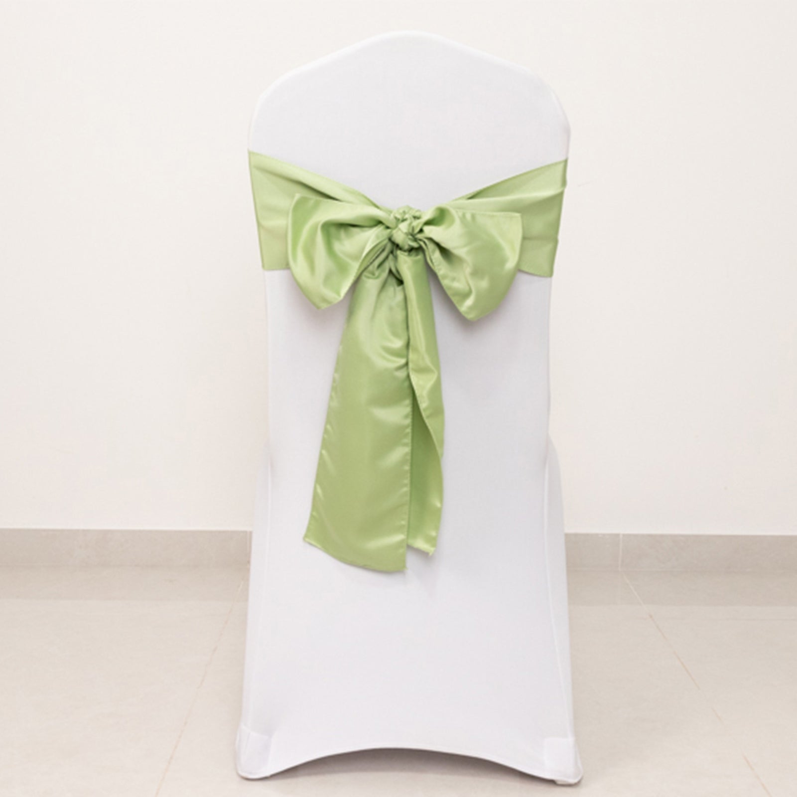 Sage green satin chair sash tied in a bow on a white chair.