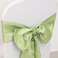 Sage green satin chair sash bow on a white chair.