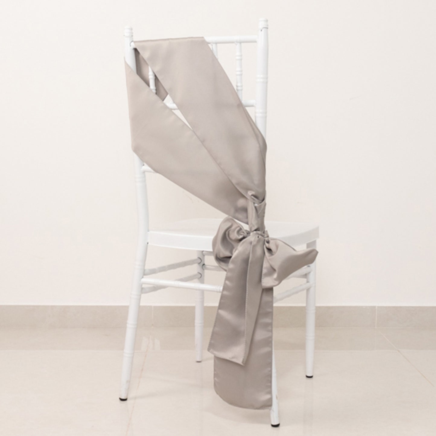 Silver satin chair sash bow on a white chair.