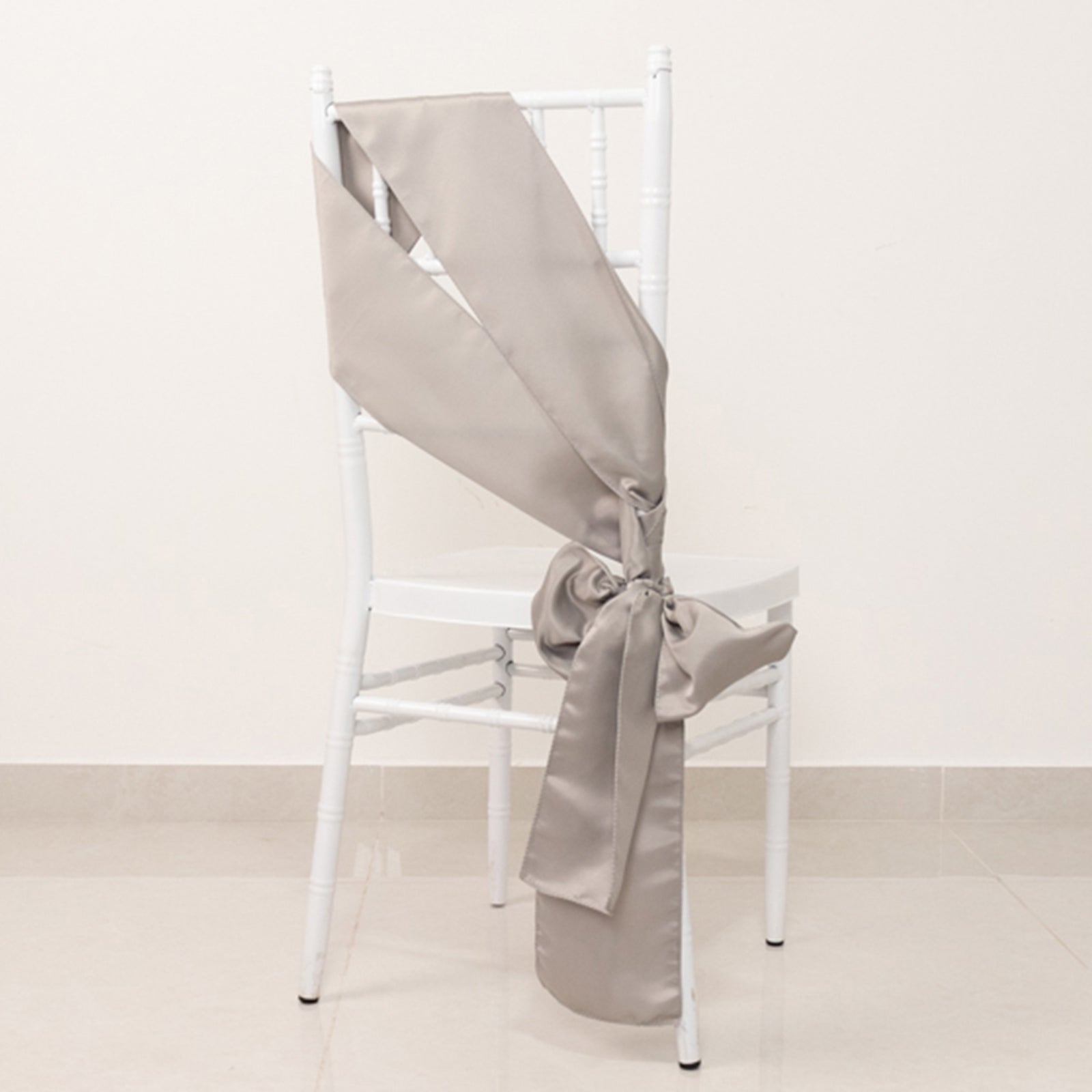 Silver satin chair sash bow on a white chair.