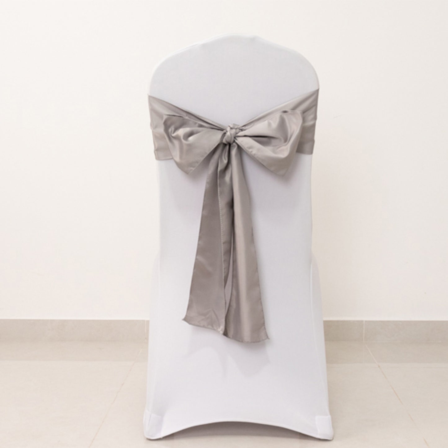 Silver satin chair sash bow on a white chair.