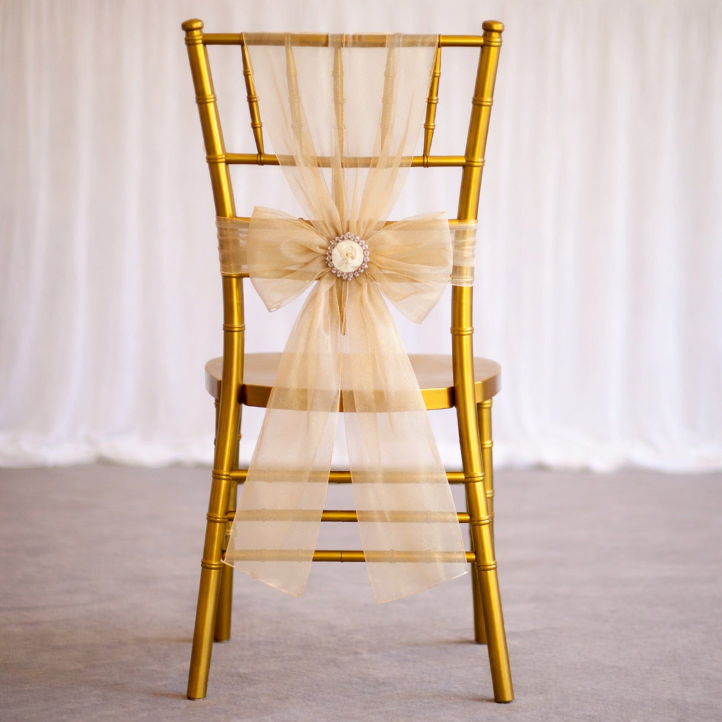 Champagne organza chair sash tied in a bow on a gold chair.