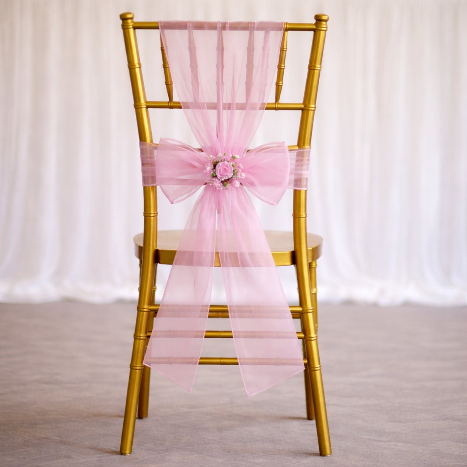 Pink organza chair sash bow on a gold chair for weddings.