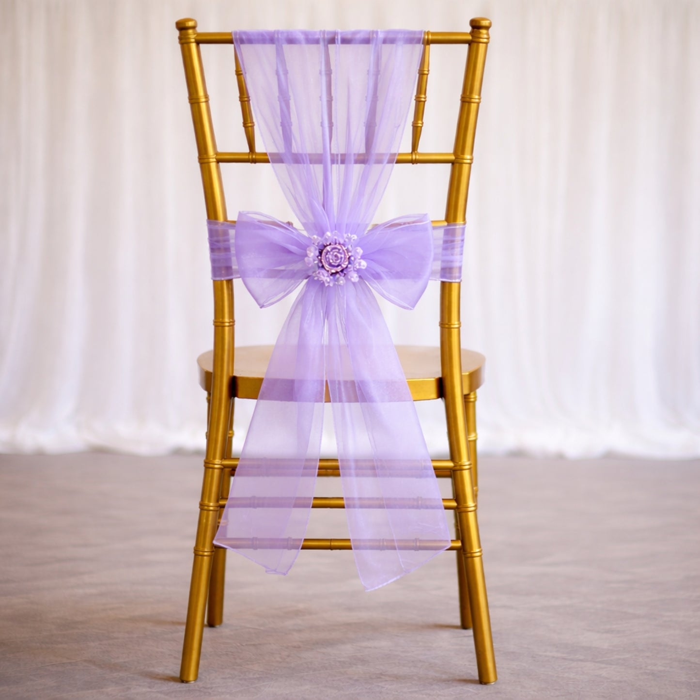 Purple organza chair sash bow on a gold chair for weddings.