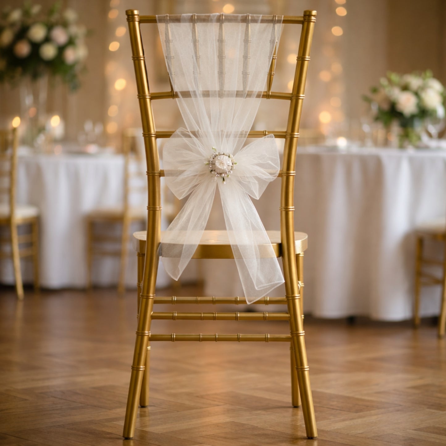White organza chair sash on a gold chair at a wedding setting.