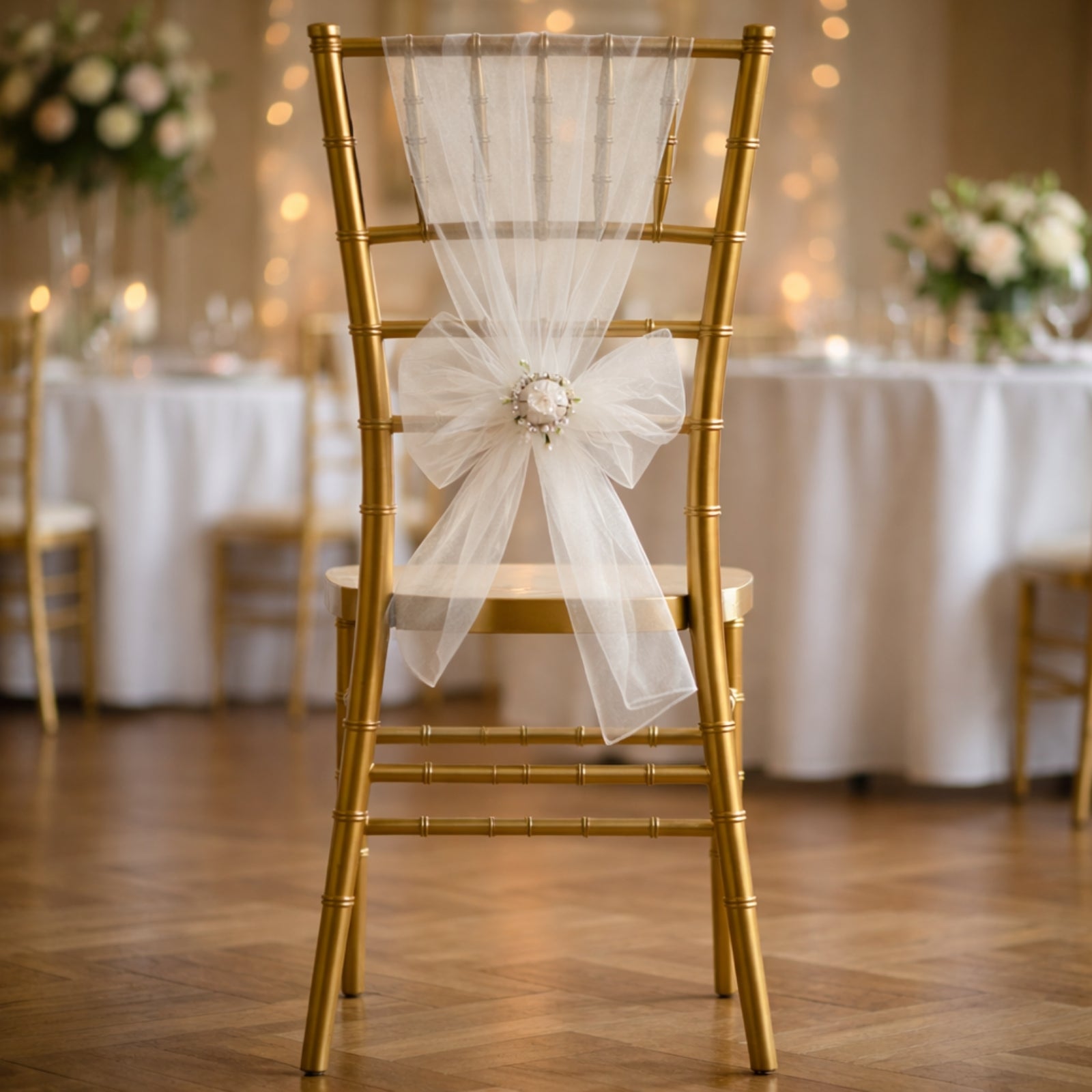 White organza chair sash on a gold chair at a wedding setting.
