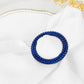 Royal blue diamond circle napkin ring pin brooch on a white fabric.