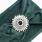 Silver metal snowflake chair sash band buckle with rhinestones on green fabric.