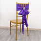 Purple bow with silver metal snowflake buckle and rhinestones on a chair.