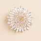 Silver metal snowflake brooch pin with diamonds and rhinestones.
