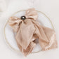 Black pearl floral metal chair sash bow pin with gold rim on a napkin.