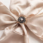Black pearl floral chair sash bow pin with gold rim on satin fabric.