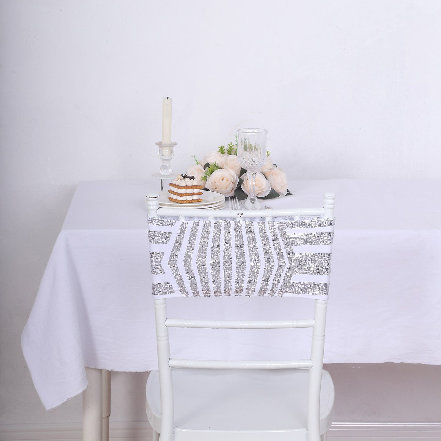 Silver sequin chair sash bands on a white chair at a dining table.