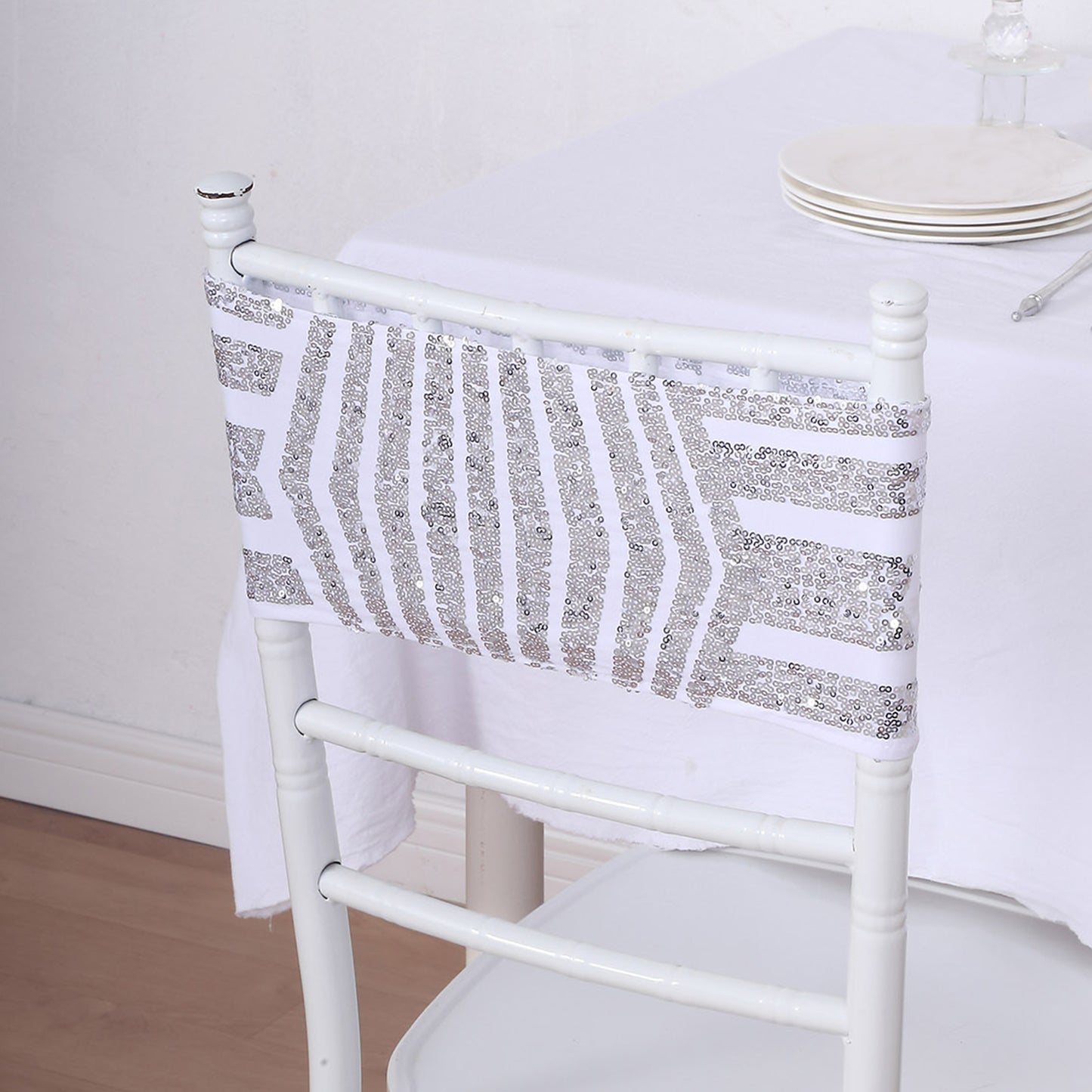 Silver sequin geometric stretchable chair sash on a white chair.