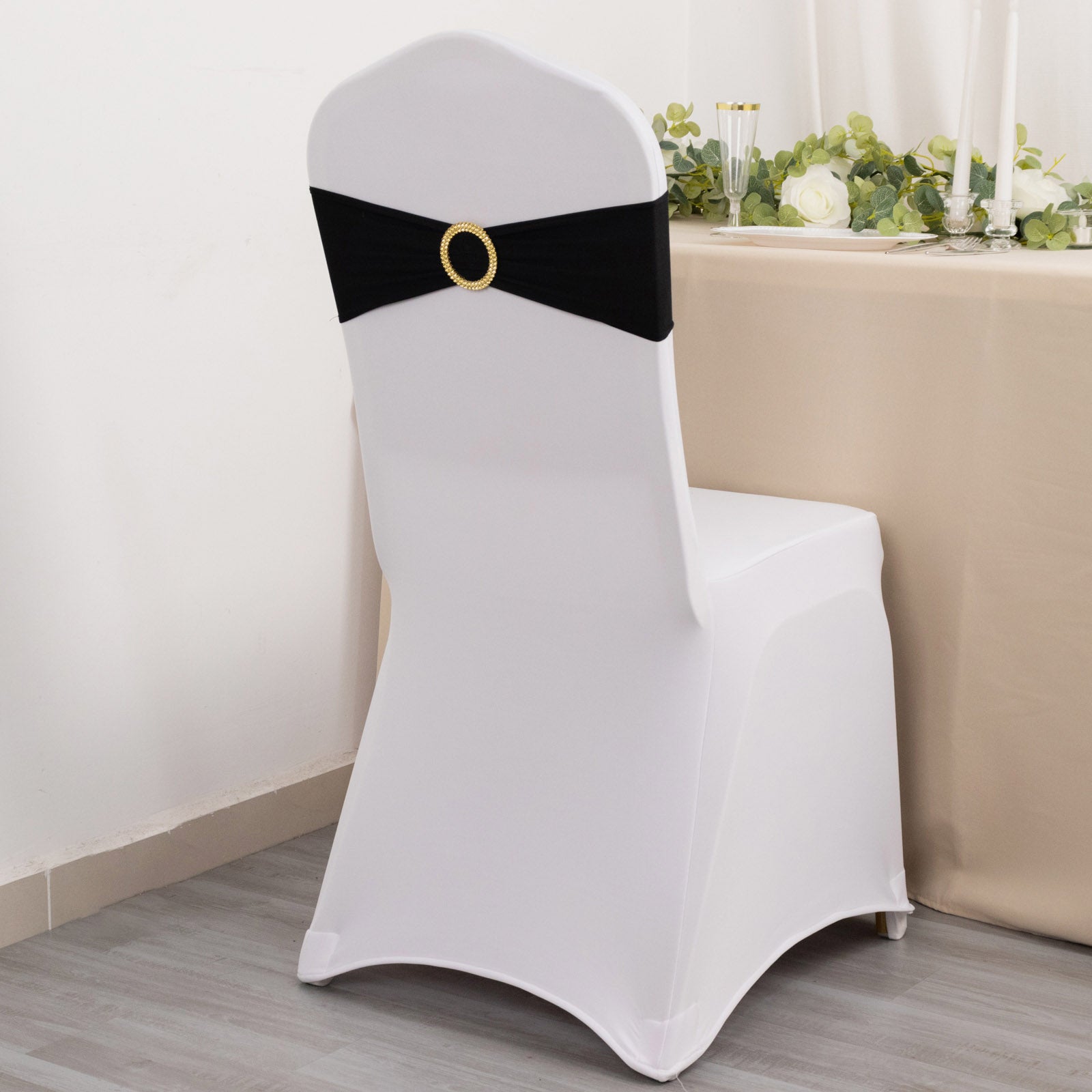 Black spandex chair sash with gold diamond buckle on a white chair.