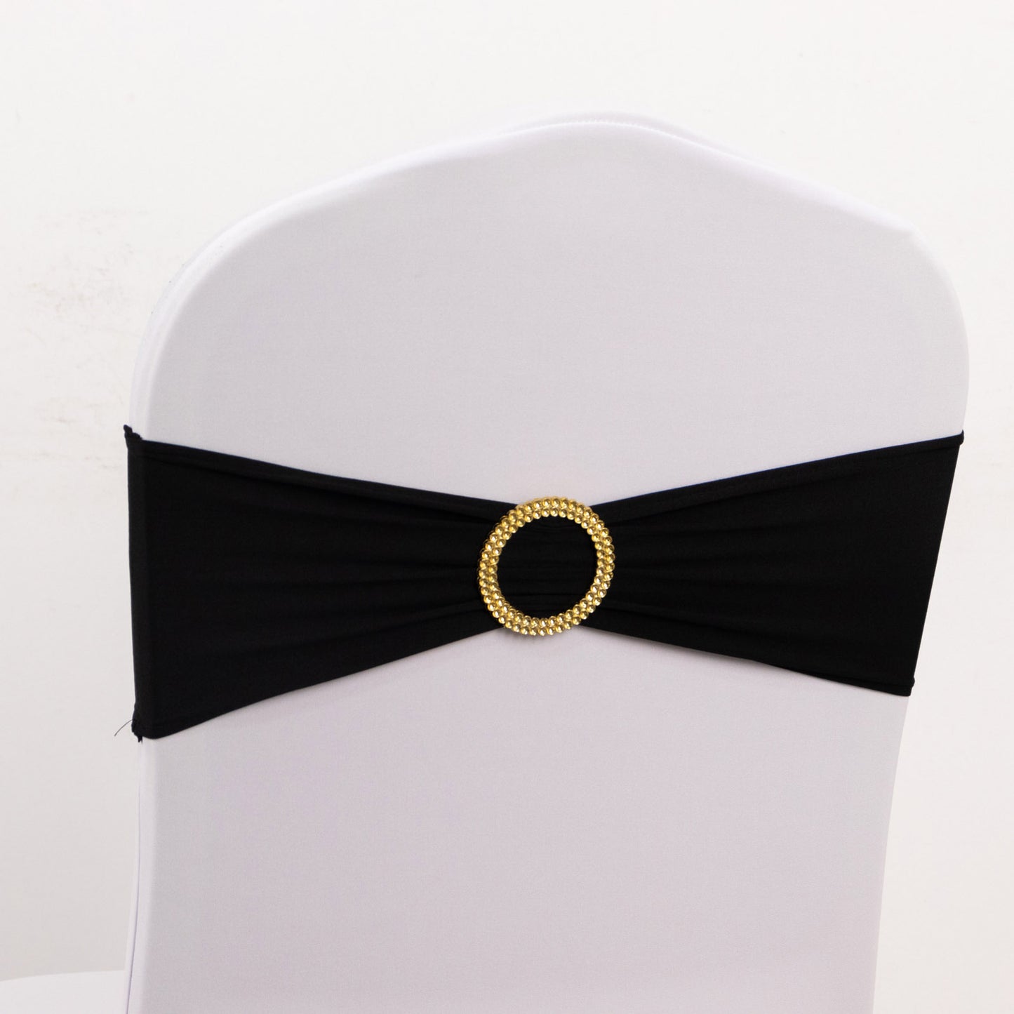 Black spandex chair sash with gold diamond buckle on a white chair.