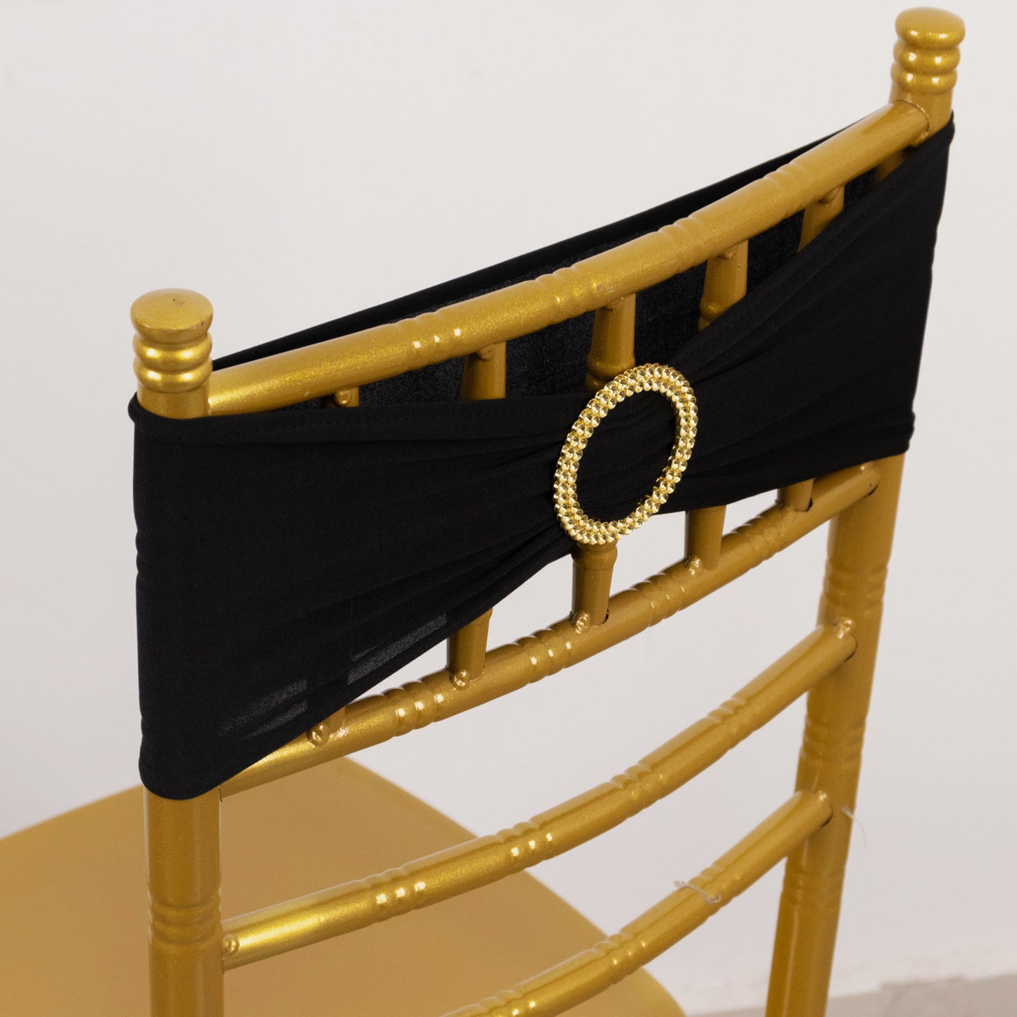 Black spandex chair sash with gold diamond buckle on a golden chair.