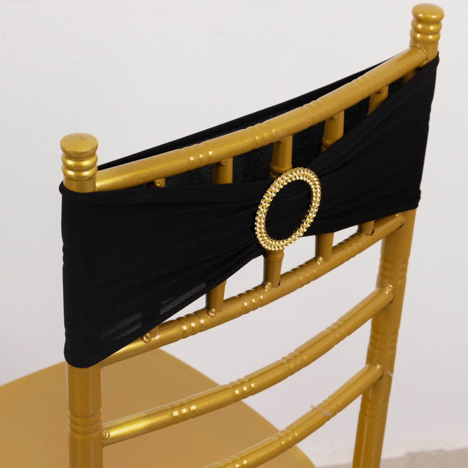 Black spandex chair sash with gold diamond buckle on a golden chair.