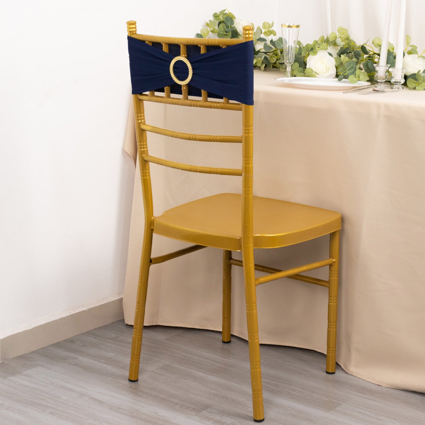 Navy blue spandex chair sash with gold diamond buckle on a gold chiavari chair.
