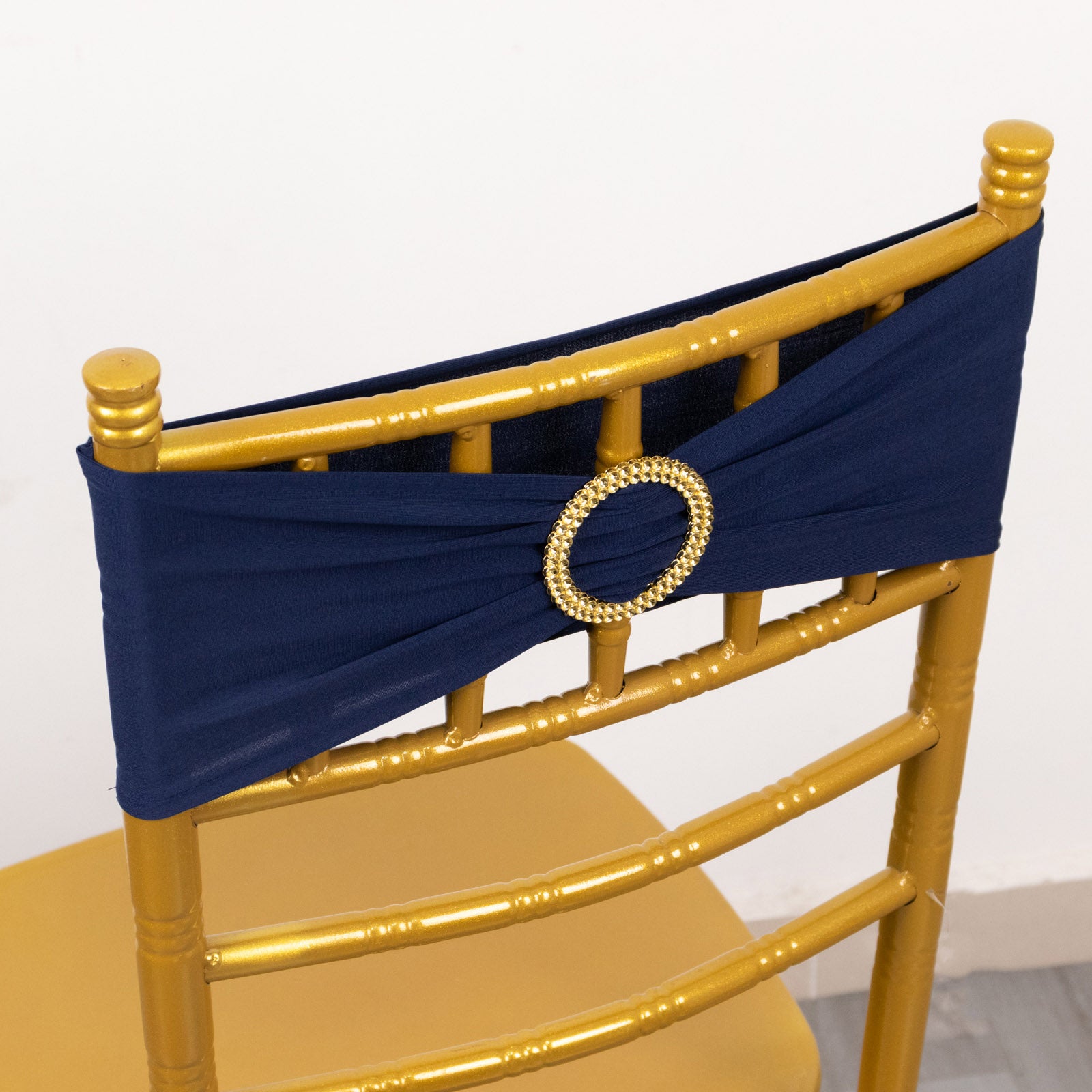 Navy blue spandex chair sash with gold diamond buckle on a gold chair.