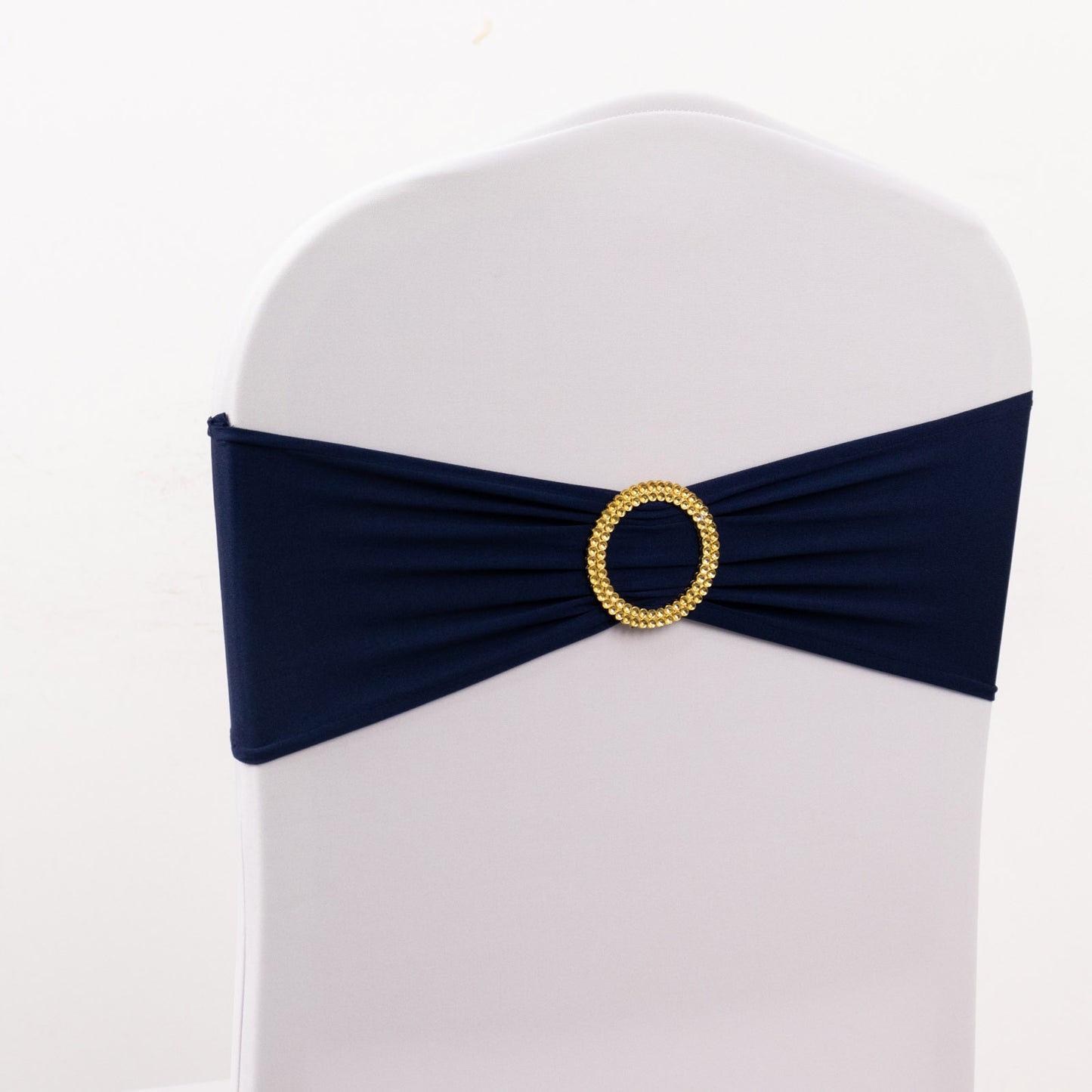 Navy blue spandex chair sash with gold diamond buckle on a white chair.