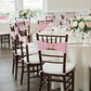 Pink spandex chair sashes with gold diamond buckles on elegant chairs.