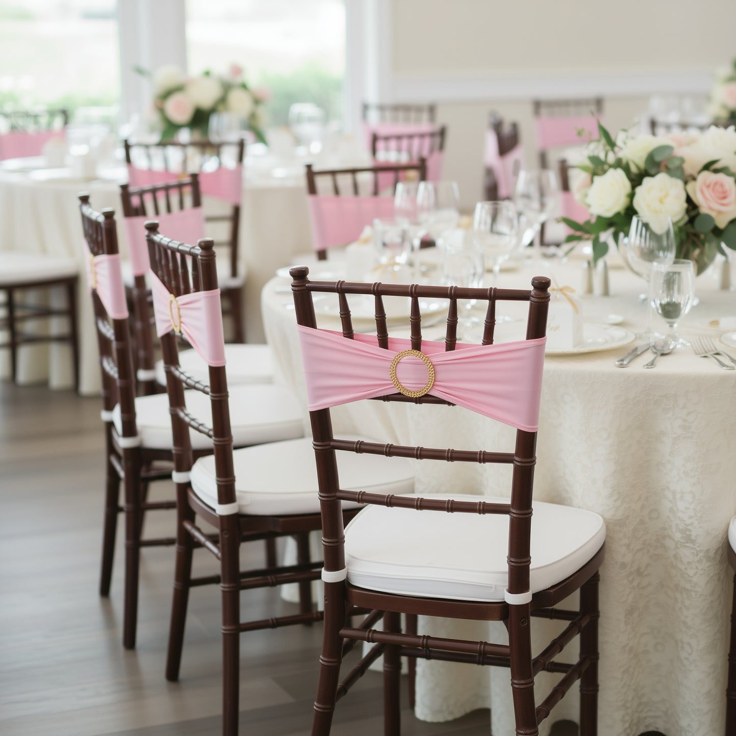 Pink spandex chair sashes with gold diamond buckles on elegant chairs.