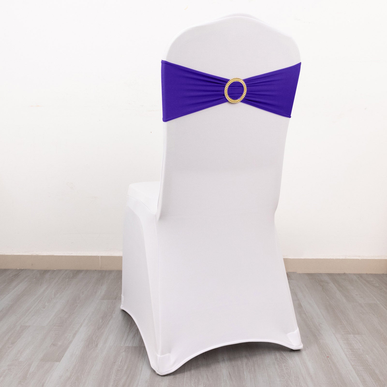 Purple spandex chair sash with gold diamond buckle on white chair.