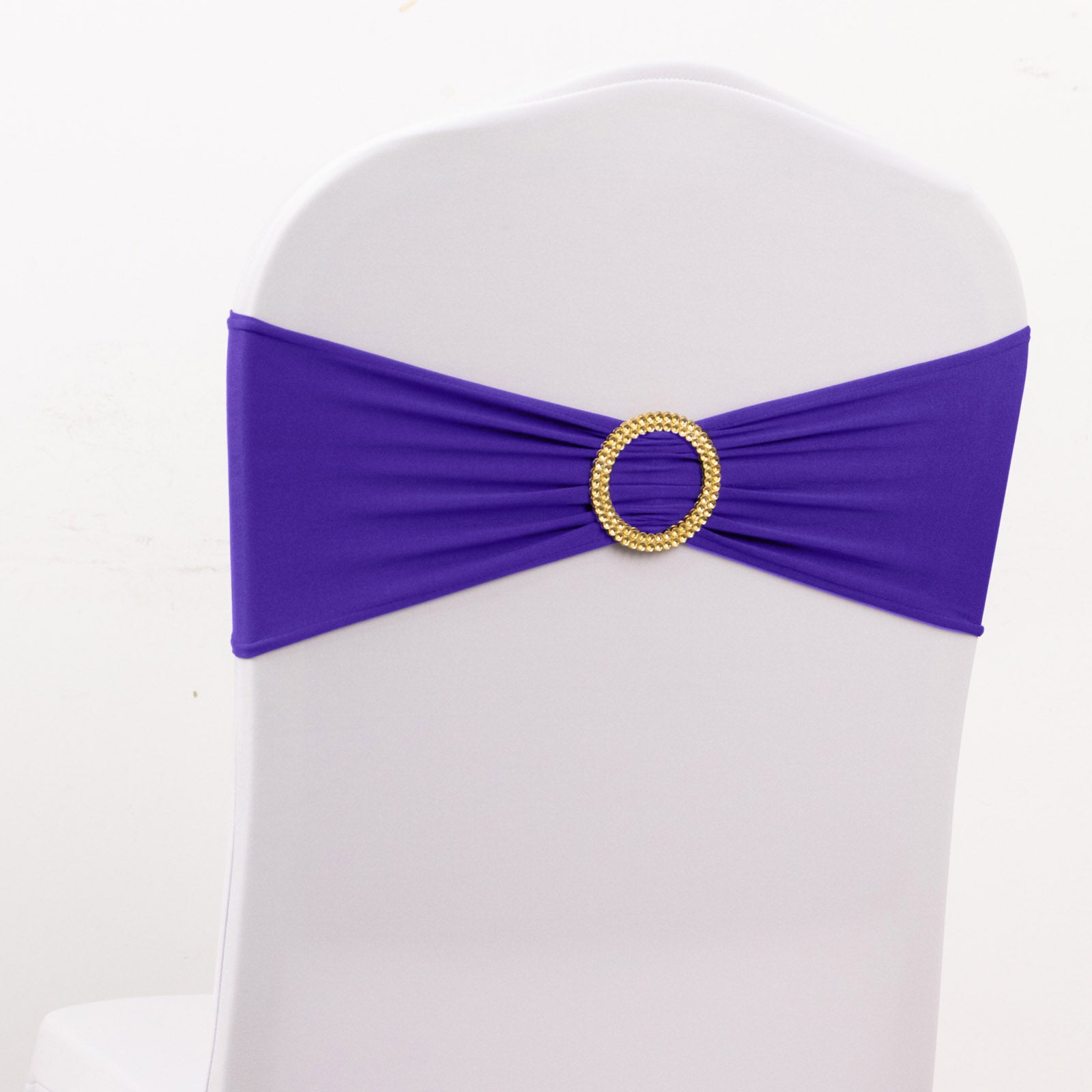 Purple spandex chair sash with gold diamond buckle on a white chair.