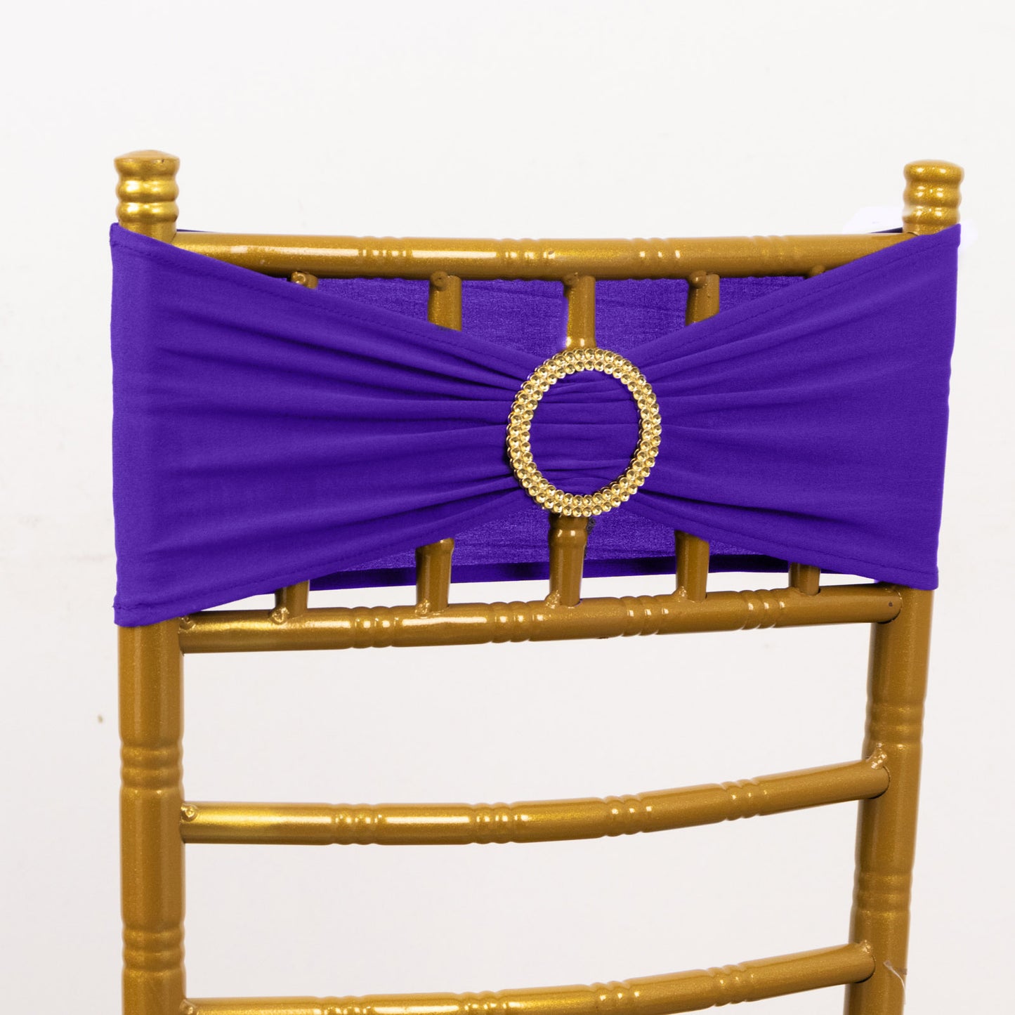 Purple spandex chair sash with gold diamond buckle on a gold chair.