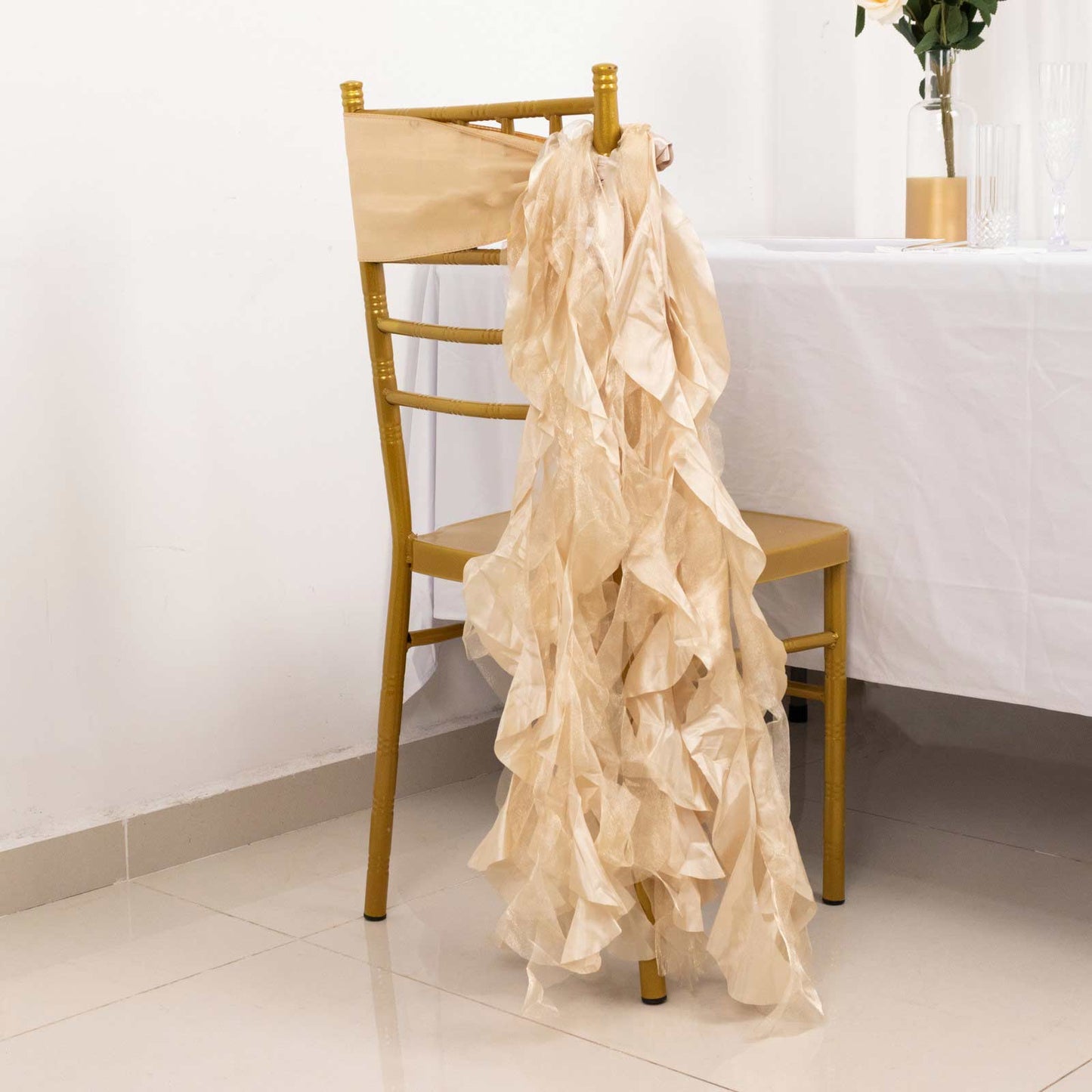 Beige curly willow chiffon satin chair sashes on a gold chair.