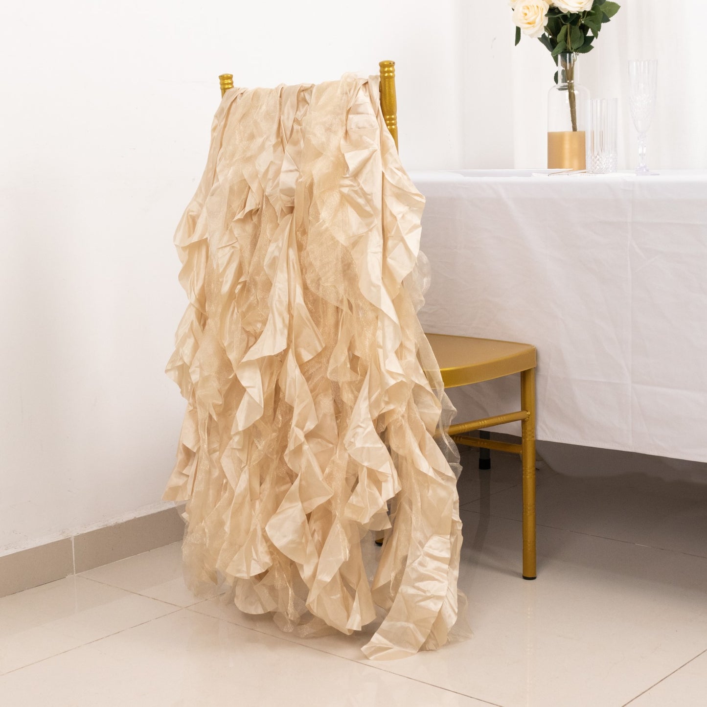 Beige curly willow chiffon satin chair sashes draped over a gold chair.