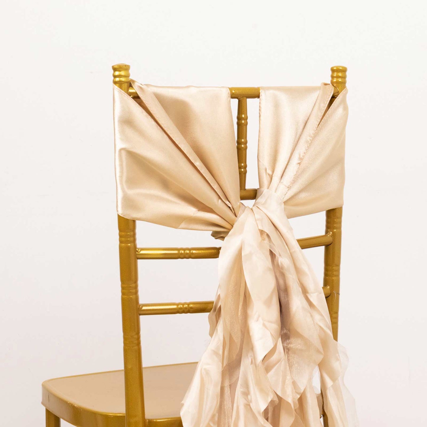 Beige chiffon satin chair sashes tied on a gold chair.