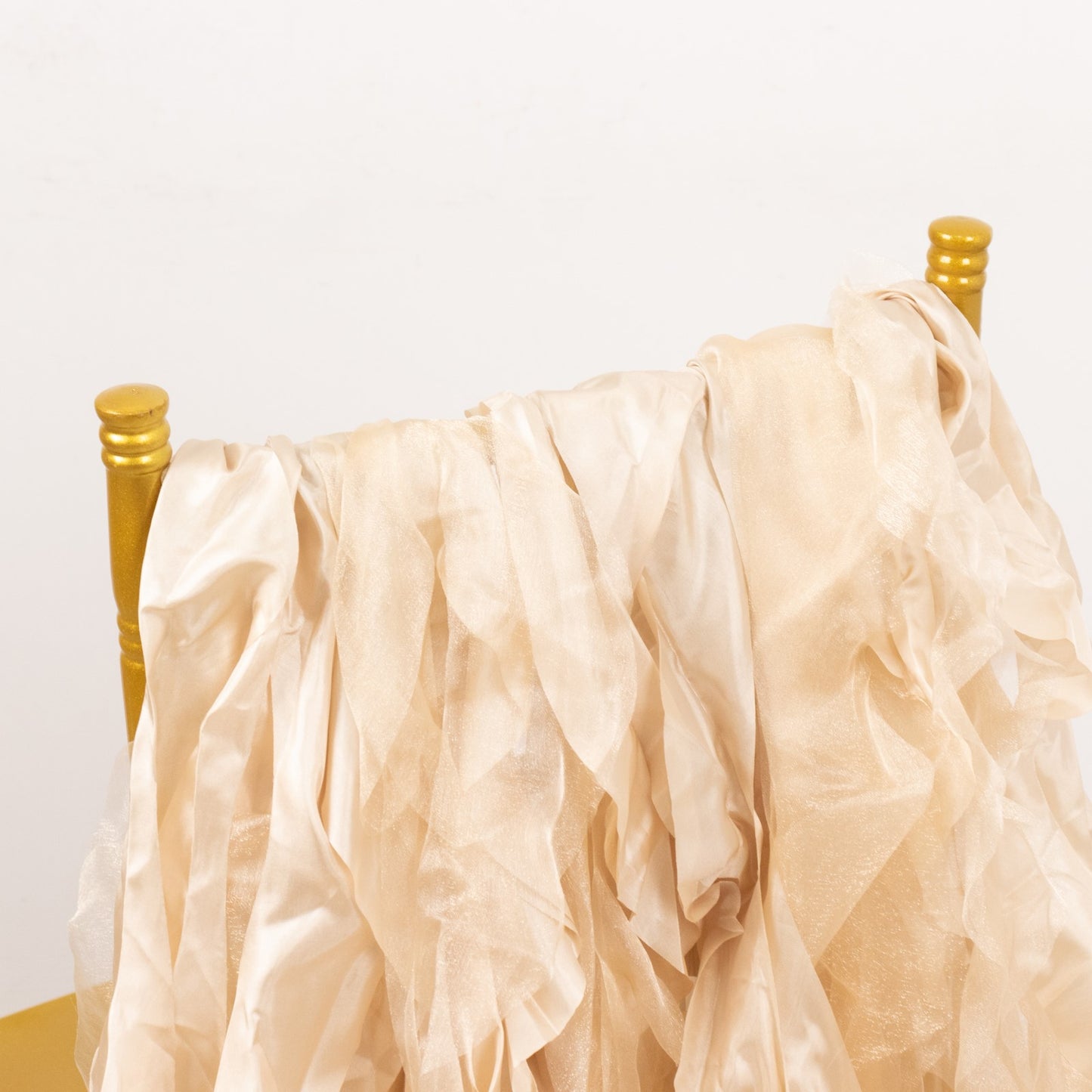 Beige curly willow chiffon satin chair sashes on a gold chair.