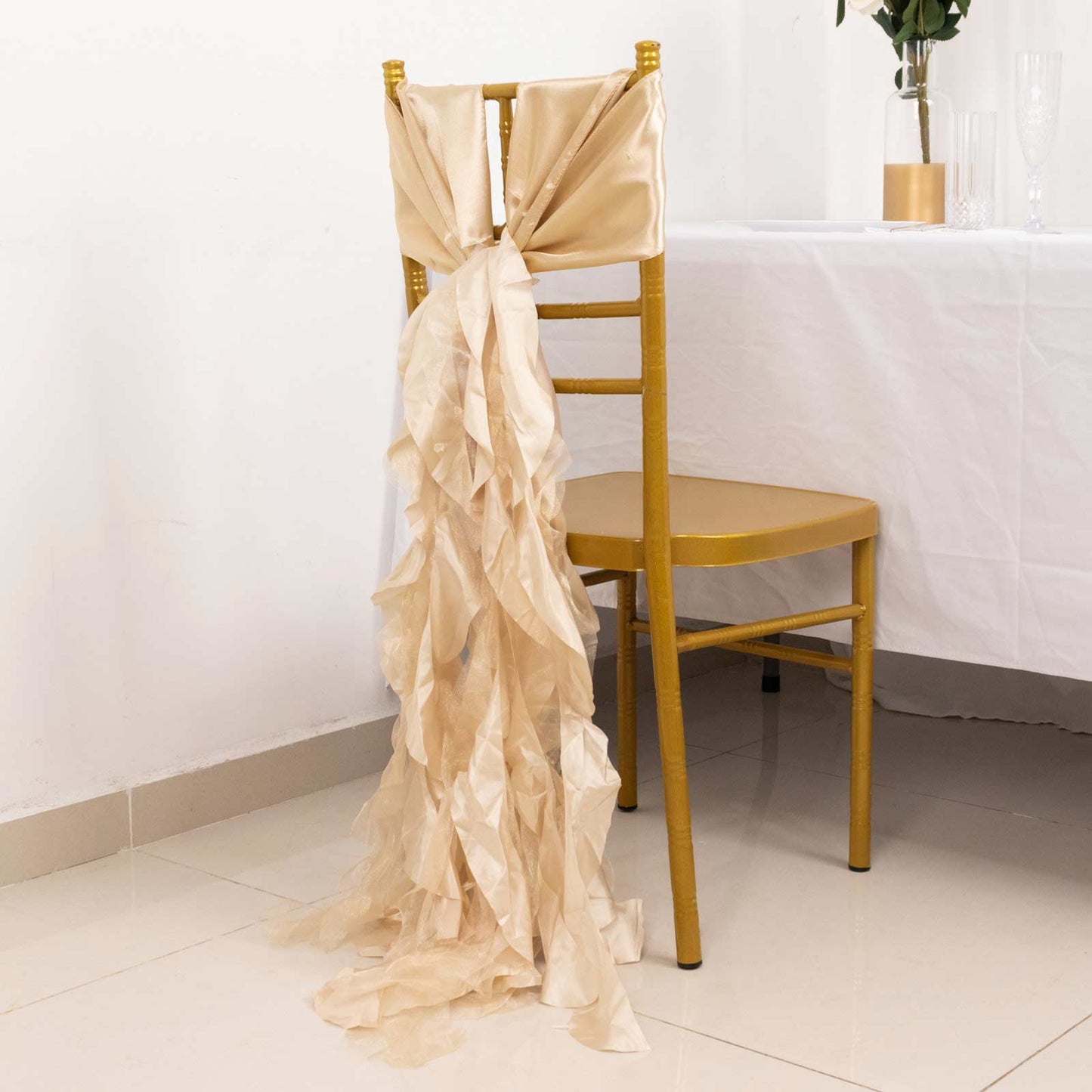 Beige curly willow chiffon satin chair sash on a gold chair.