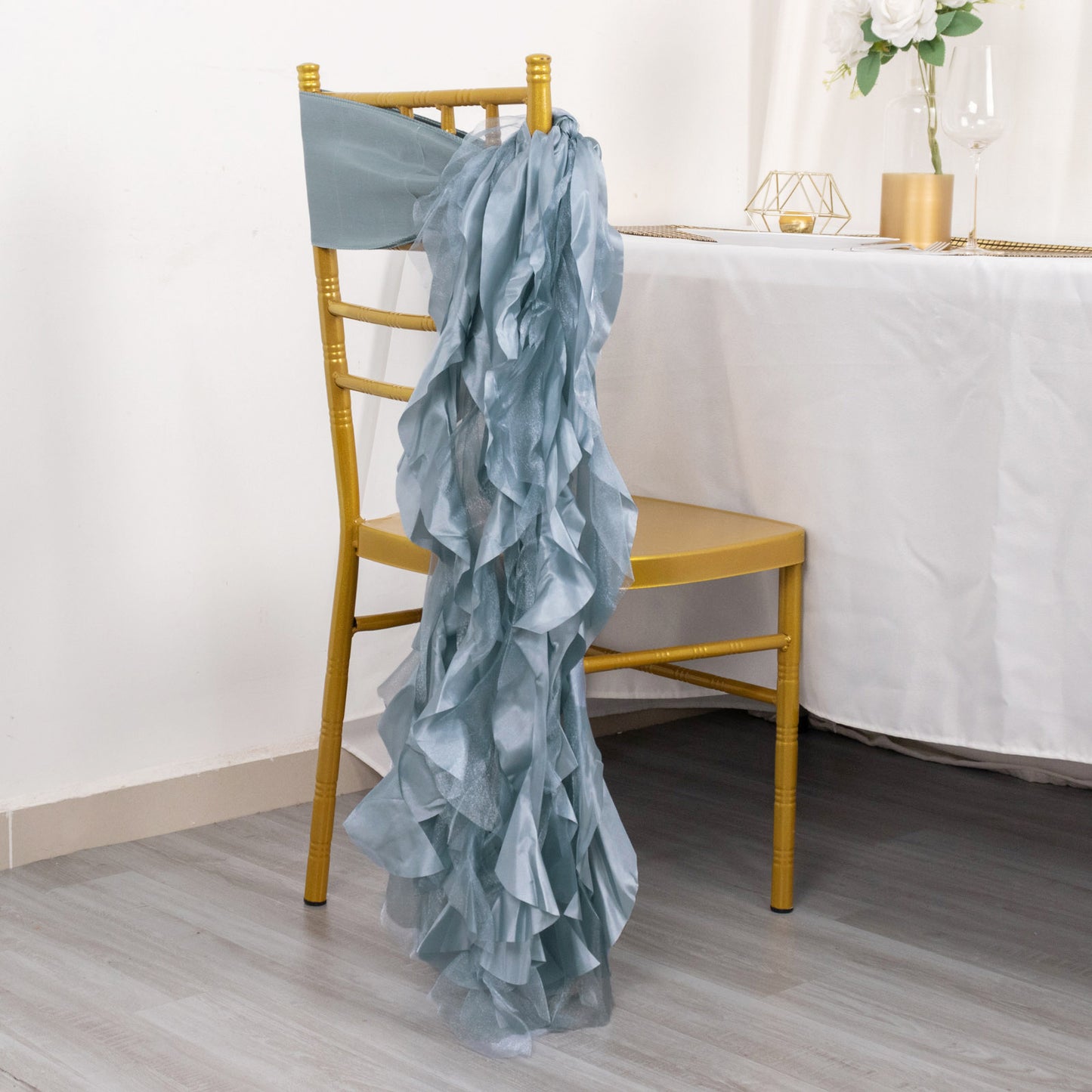 Dusty blue chiffon satin chair sash draped over a gold chair.