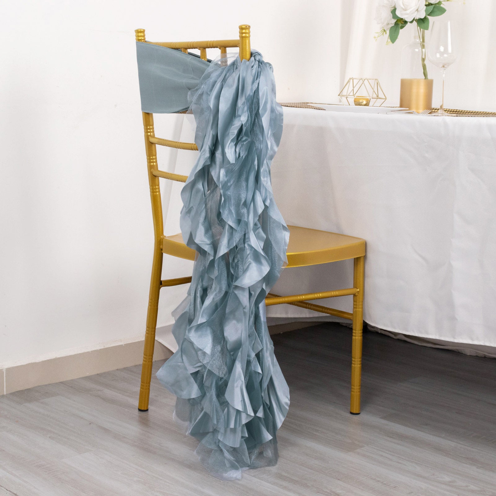 Dusty blue chiffon satin chair sash draped over a gold chair.