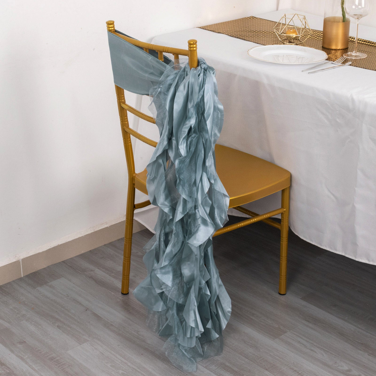 Dusty blue chiffon chair sash draped elegantly on a gold chair.