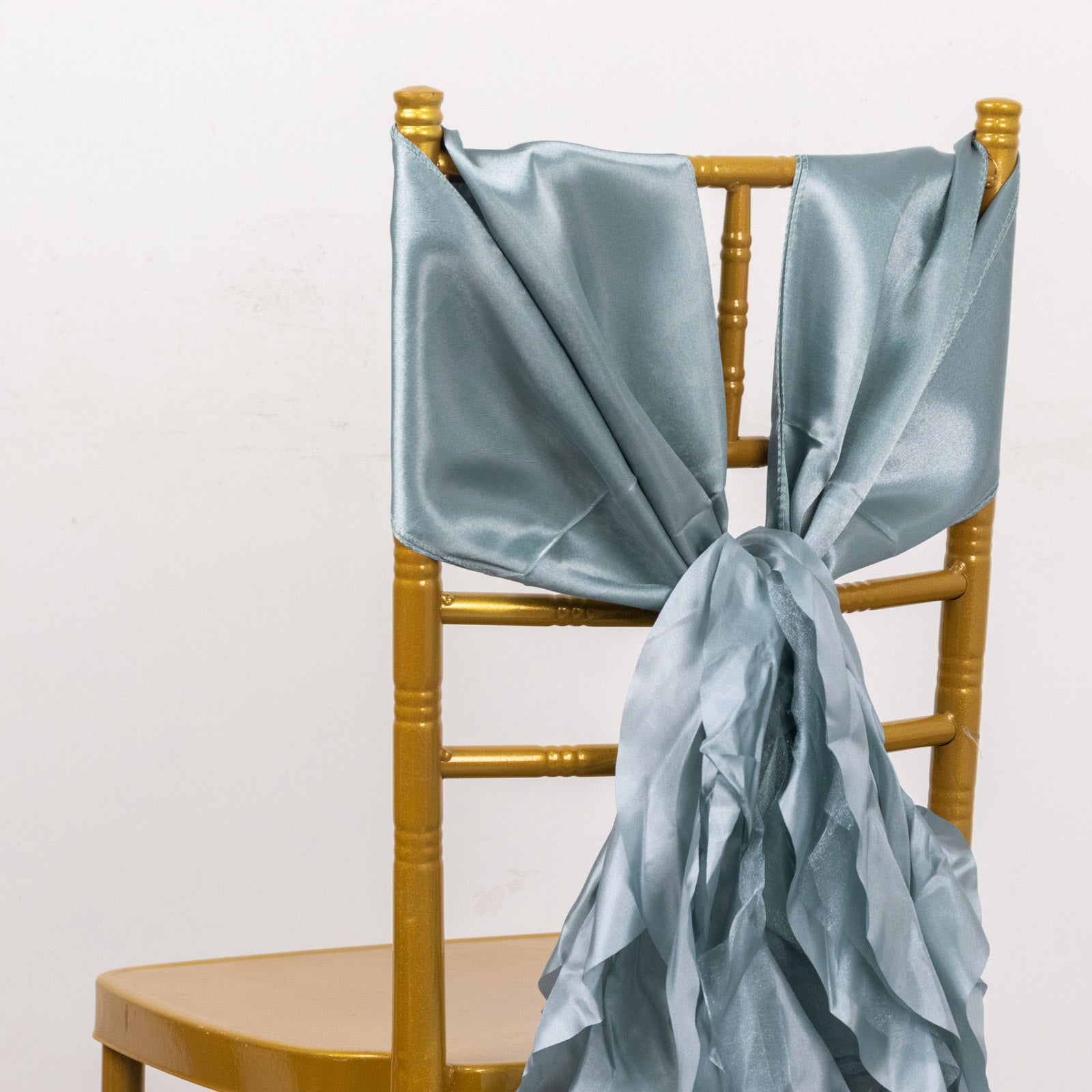Dusty blue chiffon satin chair sash tied on a gold chair.