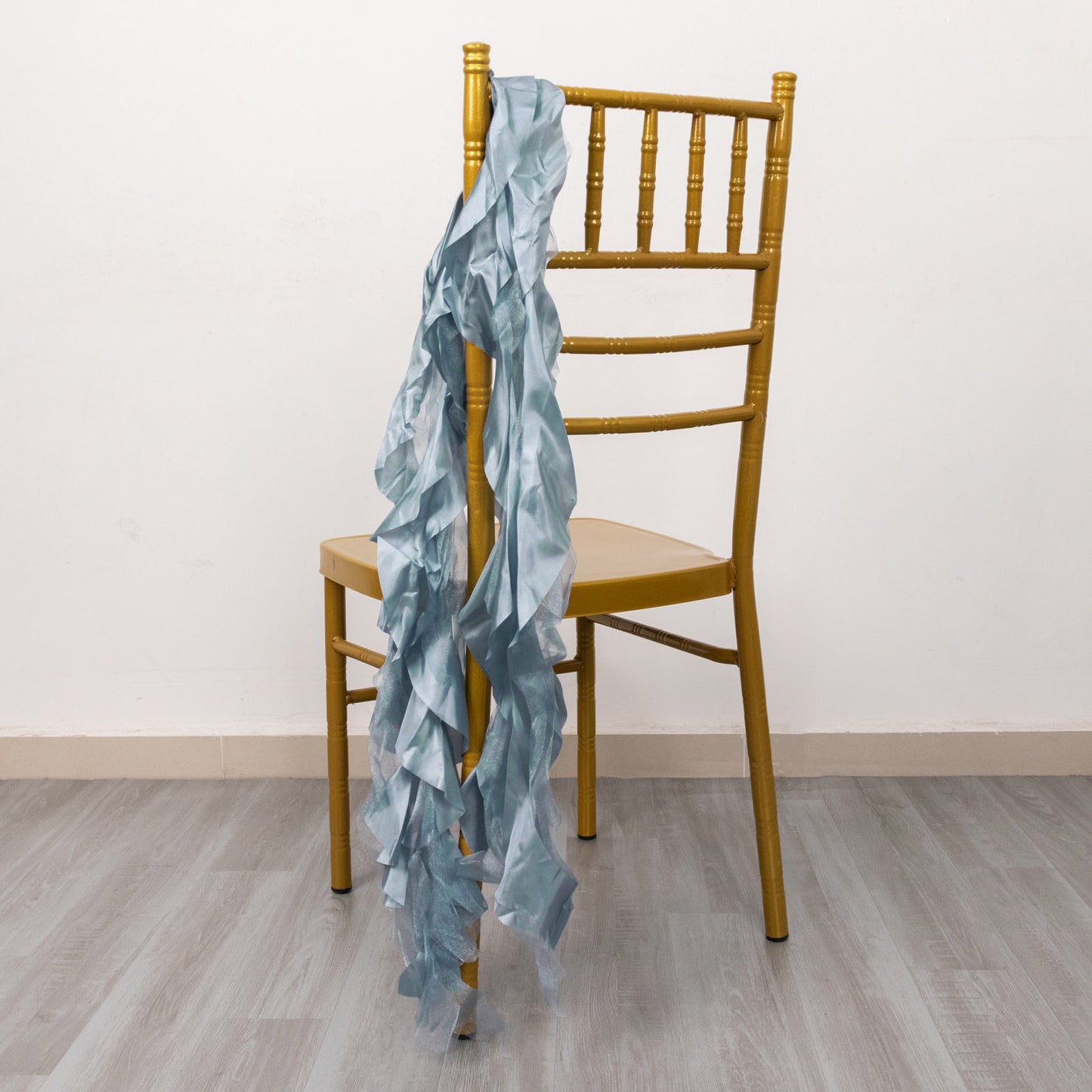 Dusty blue chiffon satin chair sashes draped on a golden chair.