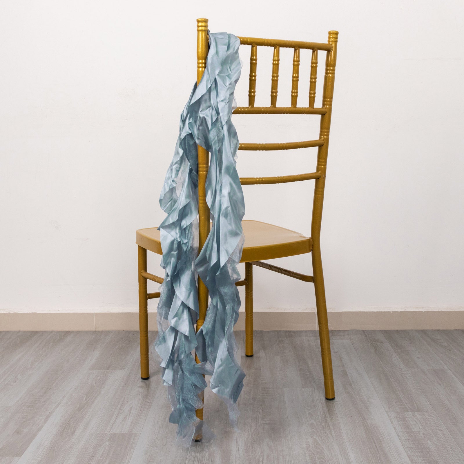 Dusty blue chiffon satin chair sashes draped on a golden chair.