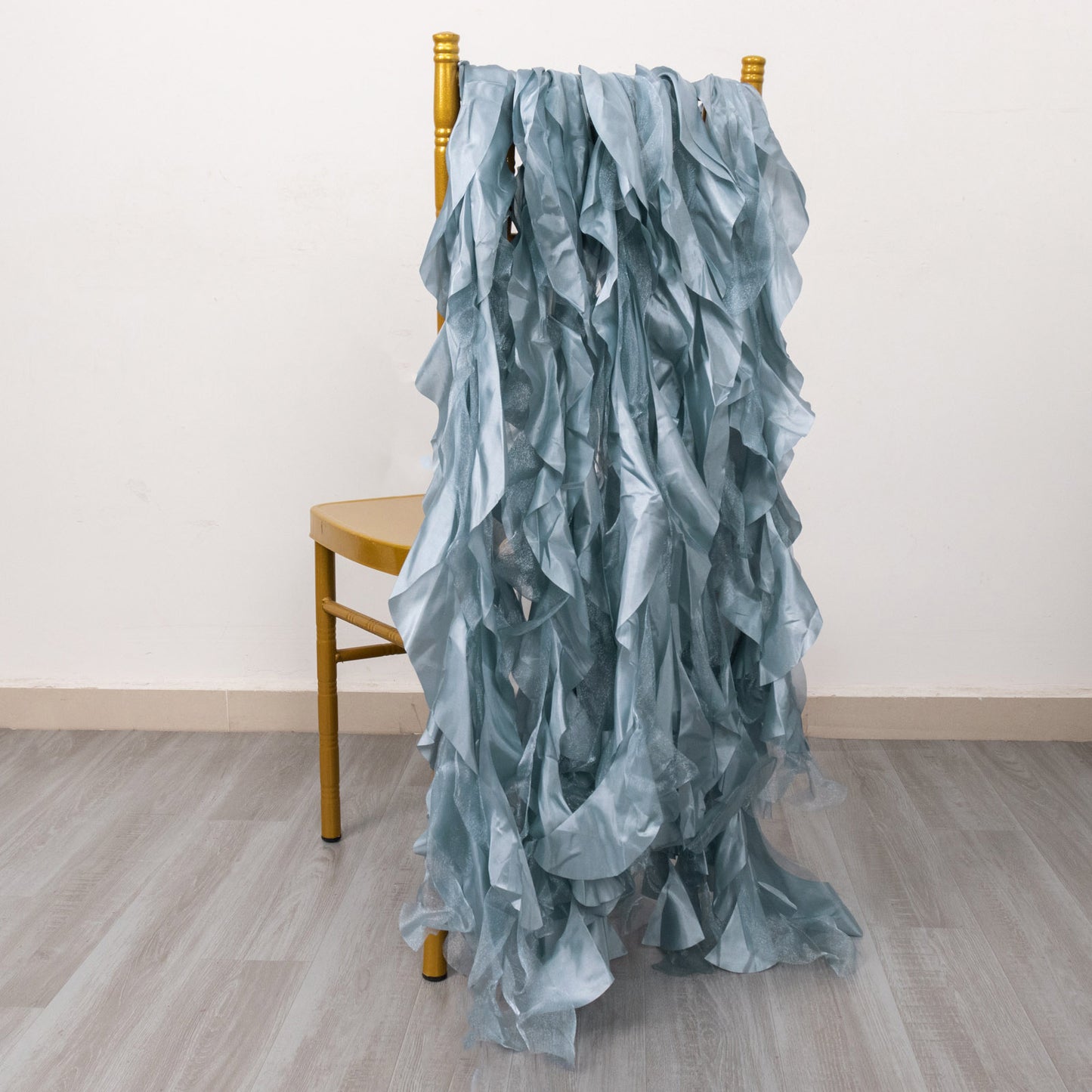 Dusty blue curly chiffon satin chair sashes draped on a chair.